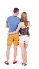 Back view of young embracing couple in shorts  hug and look.