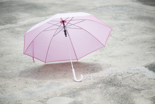 Pink umbrella outdoor on concrete floor in sunlight.