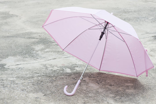 Pink umbrella outdoor on concrete floor in sunlight.