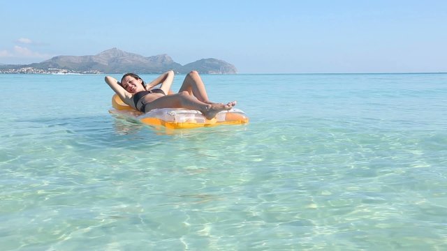 young woman on pool raft in the mediterranean sea, majorca
