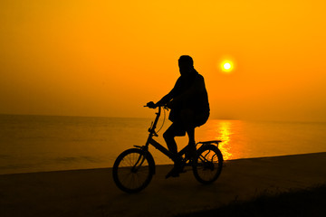 siluette of person who rides a bicycle near sea water with the s
