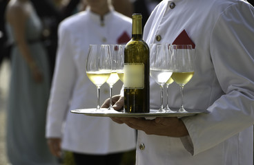 Waiters are serving vine at a wedding outdoor party