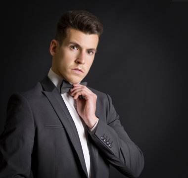 Hombre en traje de etiqueta ajusta su pajarita