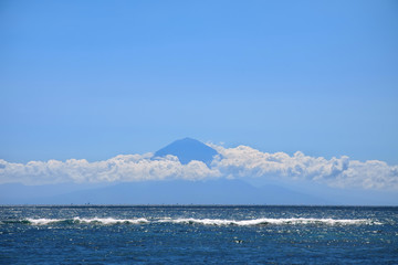 Far away silhouette of a volcano above sea waters