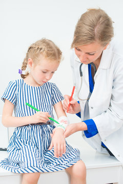 Doctor and little girl drawing bandage using felt-tip.