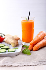 Glass of fresh carrot juice and vegetables on wooden table
