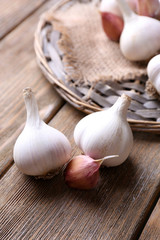 Fresh garlic on wicker mat, on wooden background