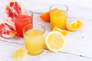 Different sliced citrus fruits and glasses of juice