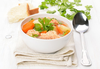 Fish soup with salmon in bowl on white wooden table