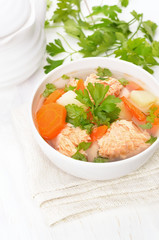 Fish soup with salmon in bowl on white wooden table