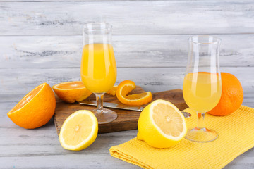 glasses of juice with fresh fruits on grey wooden table