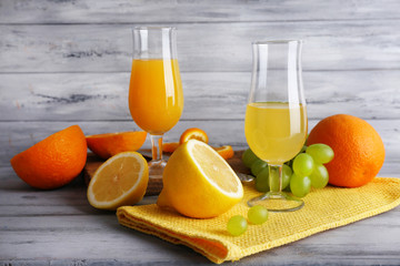 glasses of juice with fresh fruits on grey wooden table
