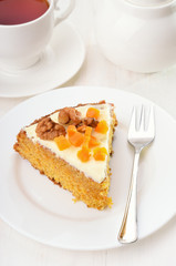 Piece of carrot cake with icing on white plate