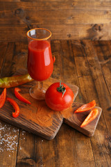 glass of tasty tomato juice and  pepper on wooden table