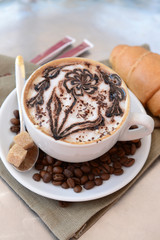 Cup of coffee with cute drawing on table, close up