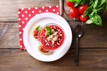 Gazpacho soup in glass bowl, on color wooden background