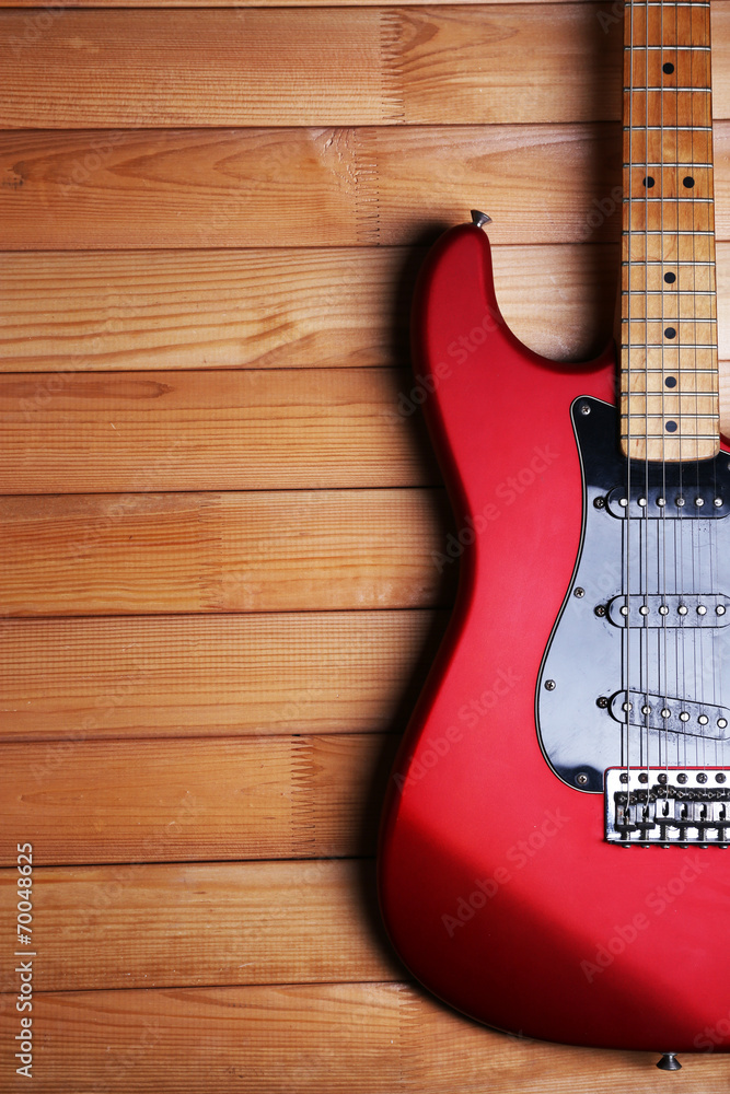 Wall mural Red guitar on wooden background