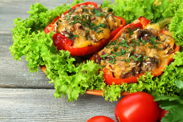 Stuffed red peppers with greens and vegetables on table close