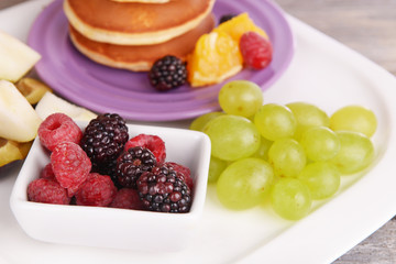 Pancake with fruits and berries on plate on wooden table