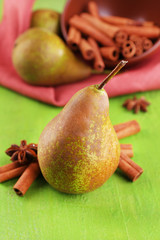 Ripe pears and cinnamon sticks  on color wooden background
