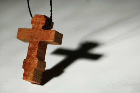 Wooden cross with deep shadow on wooden background