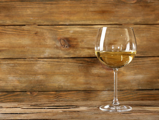 Glass of white wine on wooden table on wooden wall background
