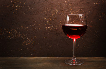 Glass of red wine on wooden table on wooden wall background