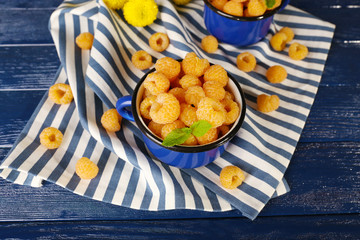 Yellow raspberries in dark blue mugs and wildflowers