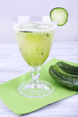 Cucumber cocktail on napkin on wooden table on light background