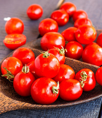 tomatoes cherry in brown wooden plate, vertically