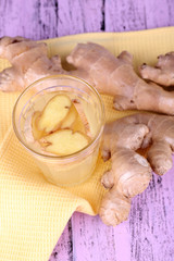Ginger drink and ginger root on napkin on wooden background