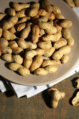 Peanuts on plate, on wooden background