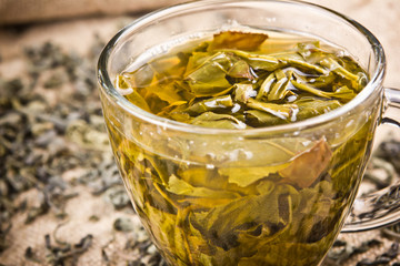 Green tea in transparent glass on linen fabric. 