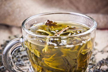 Green tea in transparent glass on linen fabric. 