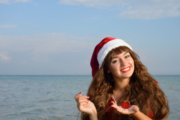 Obraz premium Happy and beautiful girl Santa Claus on the beach