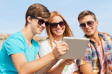 group of smiling friends with tablet pc outdoors