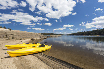 Fototapeta na wymiar Pair of Yellow Kayaks on Beautiful Mountain Lake Shore.