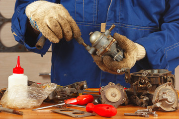 Serviceman repairing parts of the car engine in the workshop