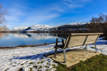 lonely bench in winter with lake view