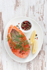 fresh salmon steak, lemon and pepper on white wooden background