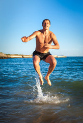 Fototapeta na wymiar Young man jumping on the beach