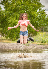 happy teen girl, jumps into a puddle