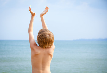 Fototapeta na wymiar boy with raised hands on the seashore