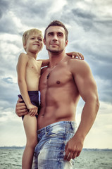 Fototapeta premium young attractive man with son staying in the sea