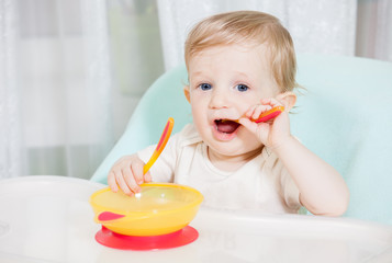 smiling baby eating food on kitchen