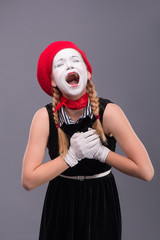 Fototapeta na wymiar Portrait of female mime in red head and with white face isolated