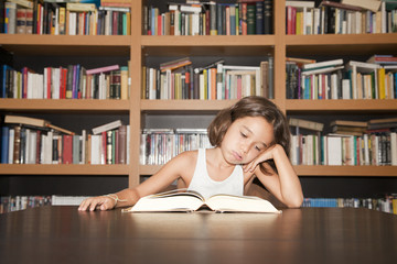 Niña estudiando junto a librería con gesto de fastidio