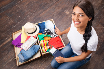 Happy girl packing her suitcase