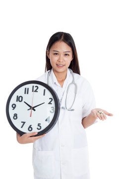 Young Asian female doctor smile with a clock and pills in hand