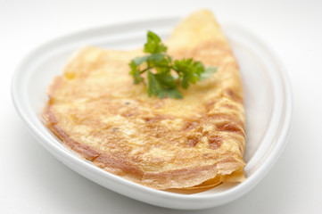 Omelet with celery leaves on white plate